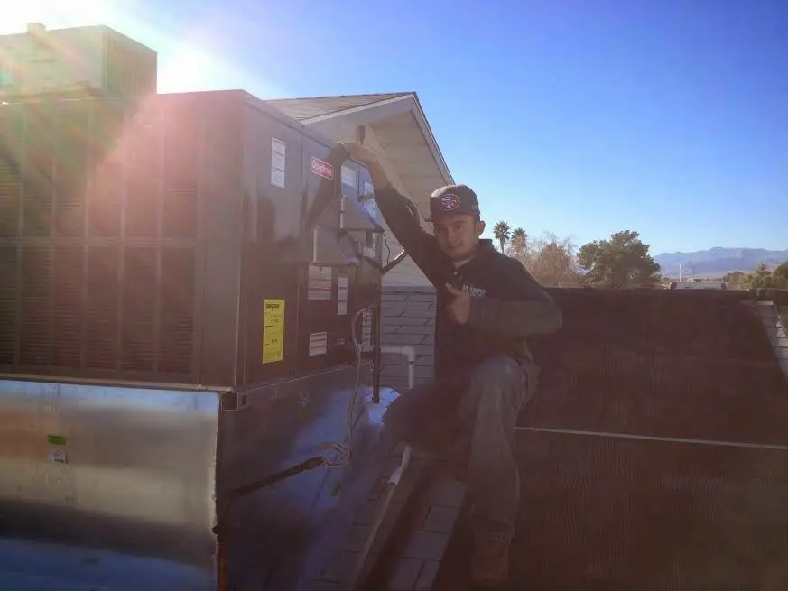 HVAC technician performing AC Tune-Up on a rooftop unit in Herndon
